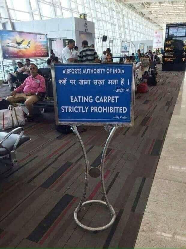 Airport sign showing a bizarre translation error prohibiting passengers from "eating carpet."