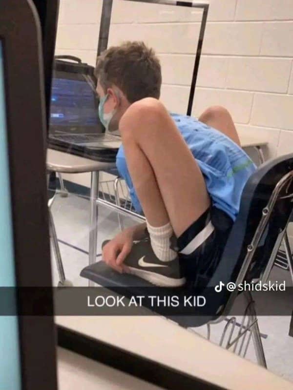 High school student sitting in classroom chair folded into an incredibly flexible pretzel shape.