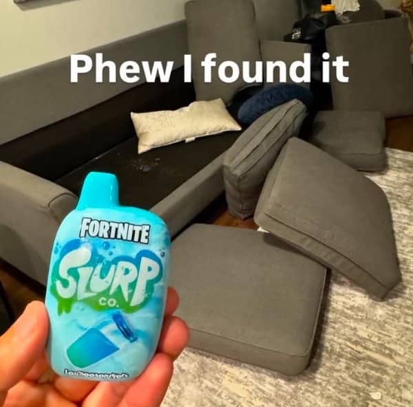 Dismantled living room couch with a hand holding a blue Fortnite Slurp Juice vape.