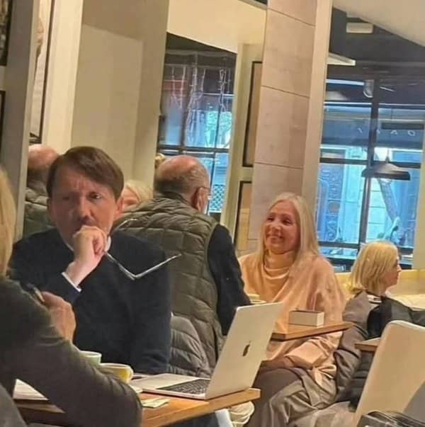 A man and a woman who look remarkably identical sitting at tables in a cafe.